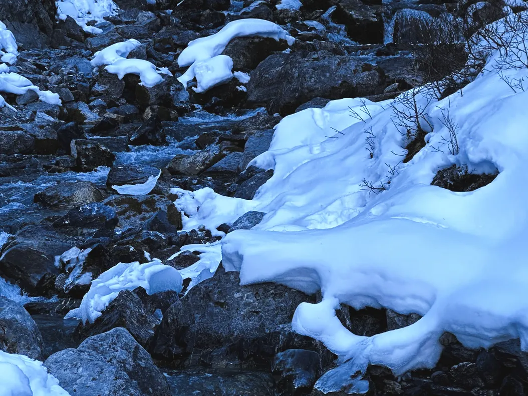 Verschneiter Fluss mit einer Schale aus Eis